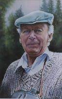 A smiling man with short grey hair wearing a blue beret. He is also wearing a while collar shirt, with is peaking out from a being knit sweater. He is looking at the camera and has black binoculars on a brown strap around his neck.