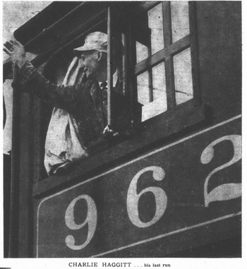 A black and white image of a man waving from the window of a train. He is smiling and looking back over his shoulder. He is wearing a pale conductor's hat, and has on a tie and jacket. "962" is printed beneath the window.