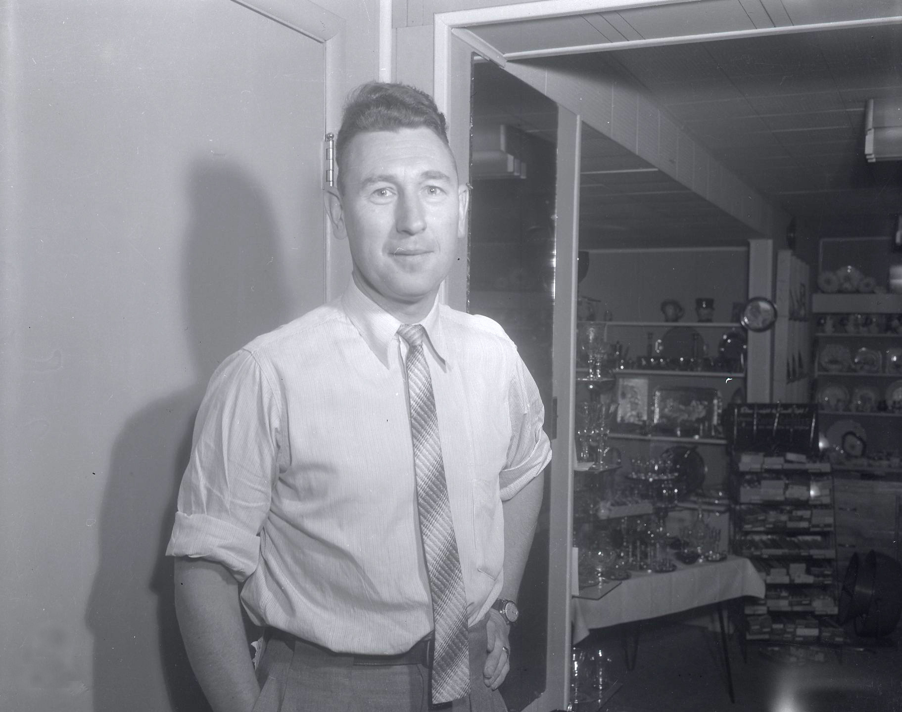 A man wearing a white shirt and a stripped tie smiling at the camera.